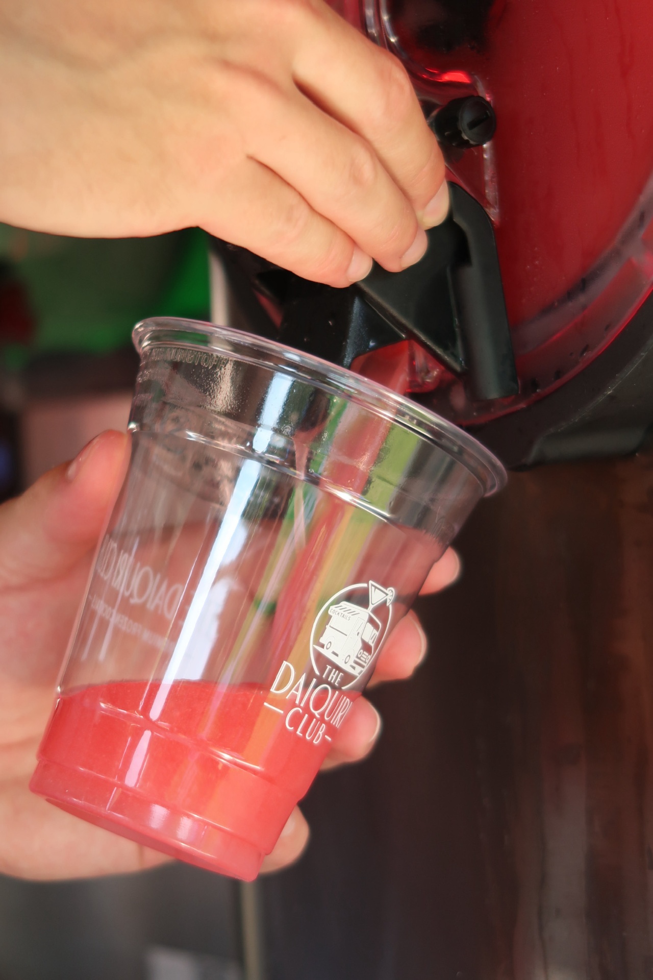 Pouring a strawberry daiquiri into a branded Daiquiri Club cup