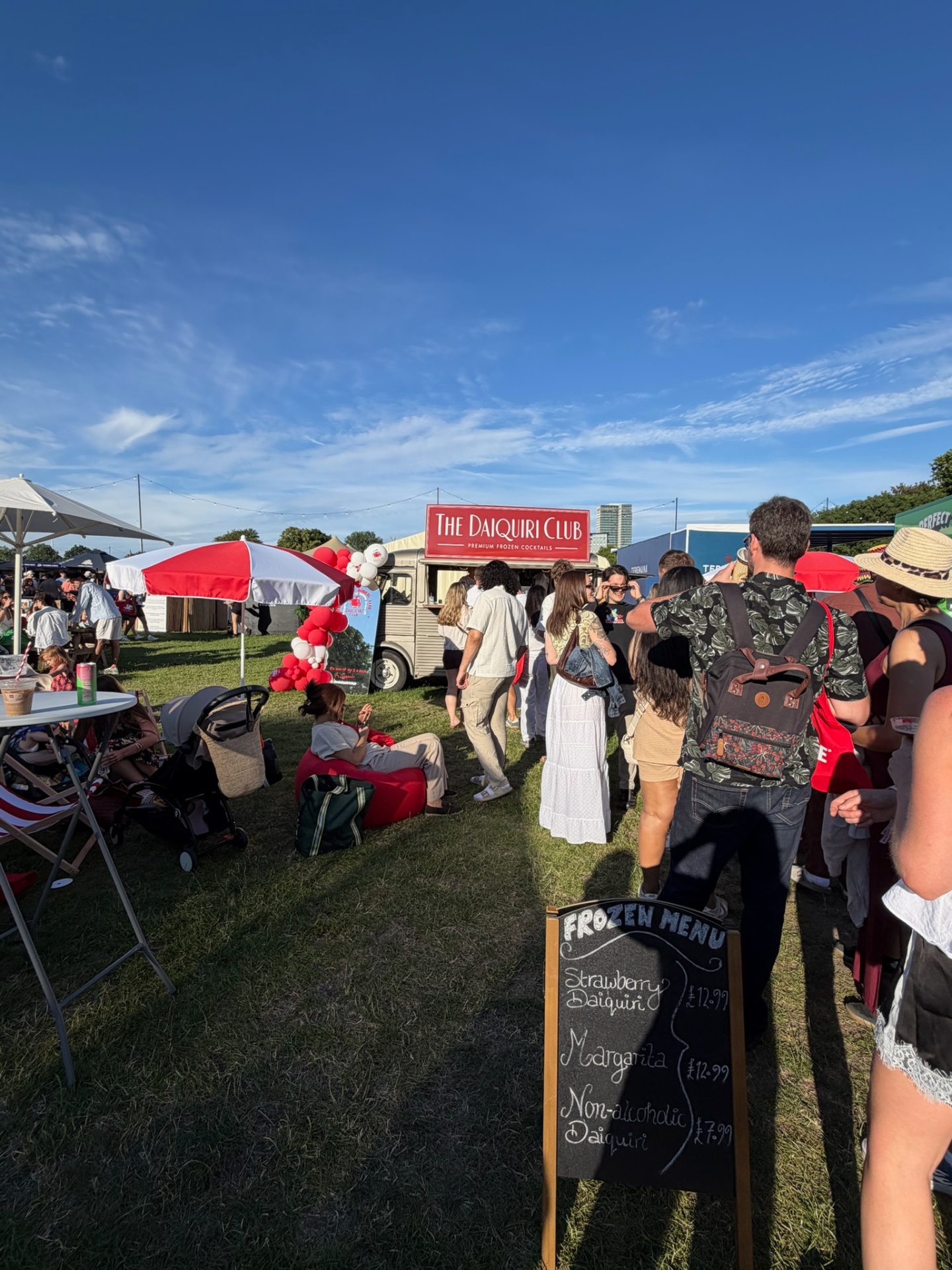 Festival crowd around The Daiquiri Club van under blue skies