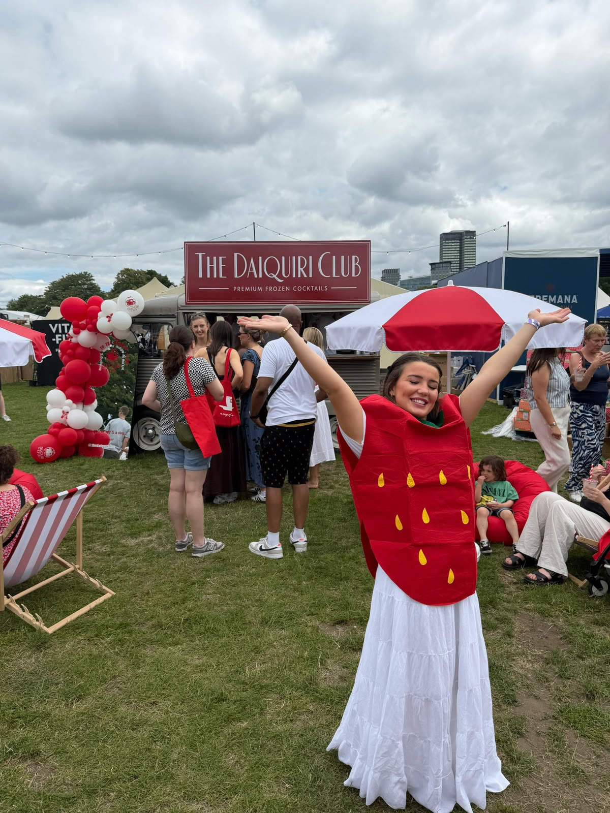 Team member in strawberry costume in front of The Daiquiri Club van at a festival
