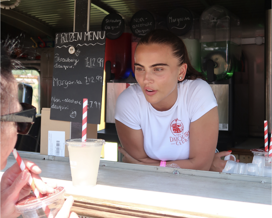 Team member serving a frozen daiquiri from the van window with chalkboard menu