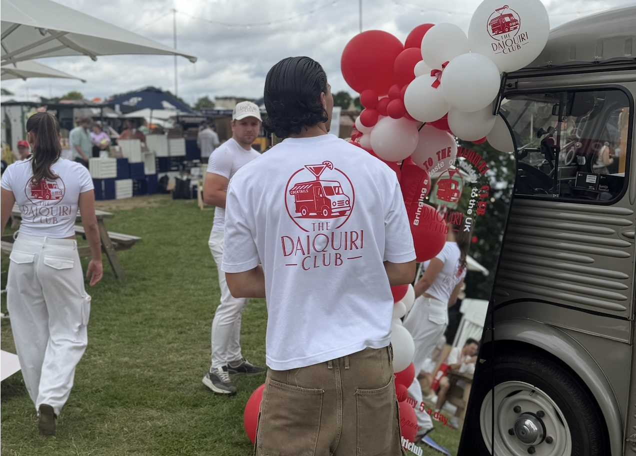 The Daiquiri Club team in branded tees beside the van and balloon arch